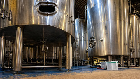 Industrial brewery with large metal tanks and a view into the interior.