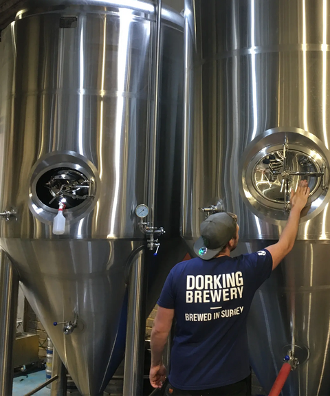 A brewer working at the stainless steel fermentation tanks inside Dorking Brewery.