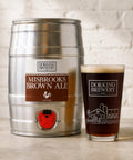 Metal keg and glass of Dorking Brewery Misbrooks Brown Ale on a wooden surface.