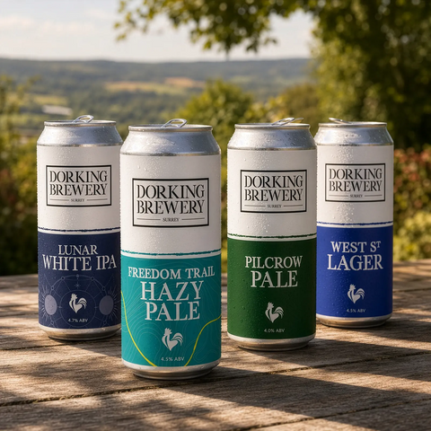Four cans of Dorking Brewery beer on a wooden surface with a scenic background